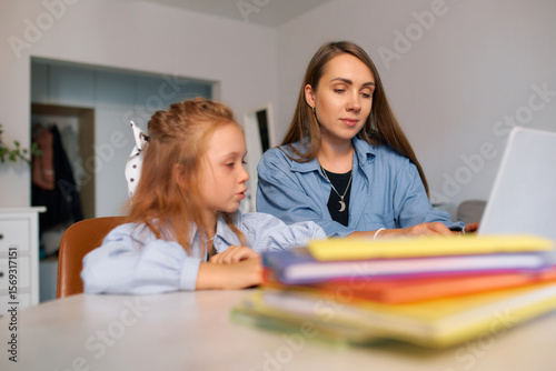 Young schoolgirl and her mother doing homework for a school lesson