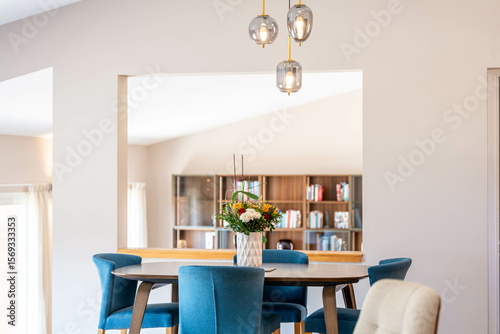 Salle    manger lumineuse avec chaises en velours bleu et vue sur biblioth  que