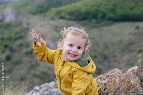 Wallpaper Mural Cute toddler in a yellow jacket enjoying and playing in the mountains at sunset. Little explorer learning through play.  Torontodigital.ca