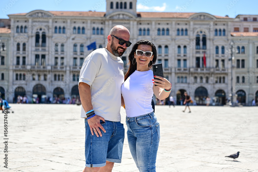 Naklejka premium Trieste ,Italy, Canal Grande .Happy smiling couple of tourists making photos near Canal Grande at Trieste .Concept of Italian gastronomy and travel. Italian couple having fun together 