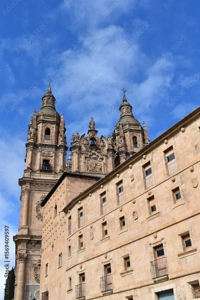 Fototapeta premium Baroque towers of the Clerecía Church against a vibrant blue sky in Salamanca Spain showcasing intricate stonework and historic architecture 