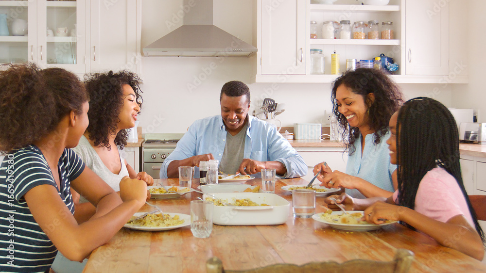 Family With Teenage Children Eating Meal In Kitchen At Home Family With Teenage Children Eating Meal In Kitchen At Home