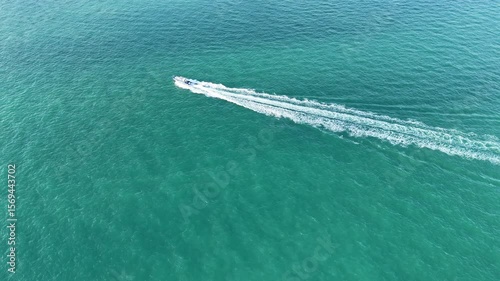 Wallpaper Mural A small speedboat cruises over clear turquoise sea leaving a white foamy trail behind. Aerial view captures the vivid color of the water and the motion of the boat.
 Torontodigital.ca