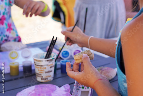 vacations and children's activities. children doing outdoor arts and crafts painting stones.