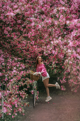 A Cheerful Woman Joyfully Riding a Bicycle Along a Beautifully Blooming Nature Path