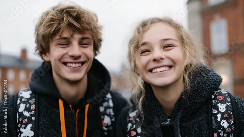 Smiling teenagers enjoying a joyful moment outdoors in a city setting during a cloudy day