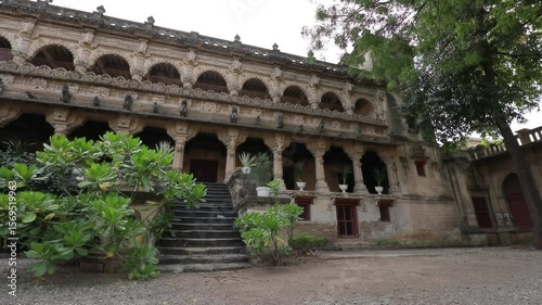 Ancient Stone Building with Archways and Steps Surrounded by Lush Greenery