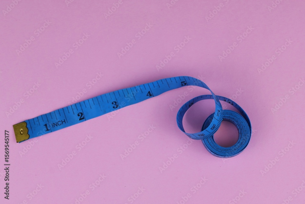 Fototapeta premium Blue measuring tape isolated on pink background. diet for weight loss concept.
