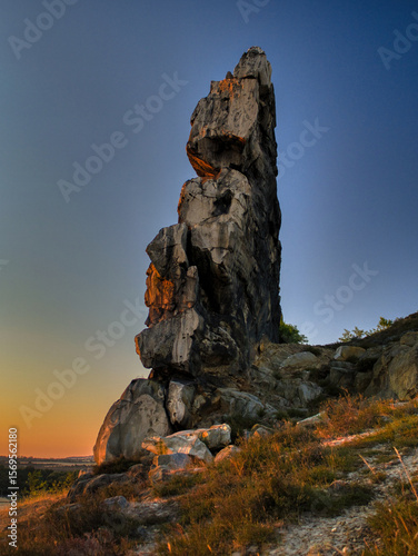 Majestic sandstone pillar of the Devil’s Wall in Germany’s Harz region illuminated by golden sunrise light. A natural wonder and geological landmark perfect for nature and travel themes.