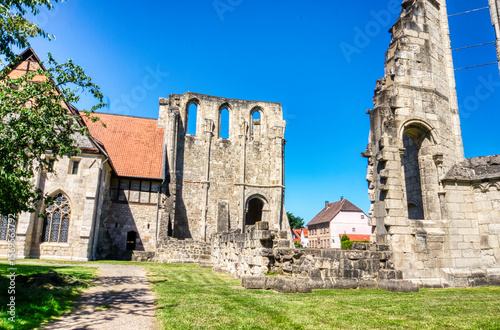 Medieval ruins of the Cistercian Walkenried Monastery in Lower Saxony, Germany. Gothic arches, stone walls, and green lawns under a clear blue sky reflect centuries of religious history