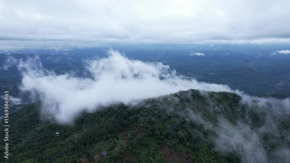 Drone view of misty clouds rolling over a vibrant green mountain range. Peaceful and majestic nature scene, great for travel or serene content Drone view of misty clouds rolling over a vibrant green mountain range. Peaceful and majestic nature scene, great for travel or serene content