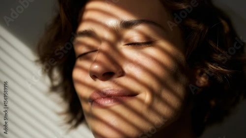 Woman enjoying sunlight through striped shadows in a serene indoor setting