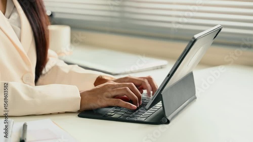 Close up of businesswoman typing on digital tablet keyboard in modern office