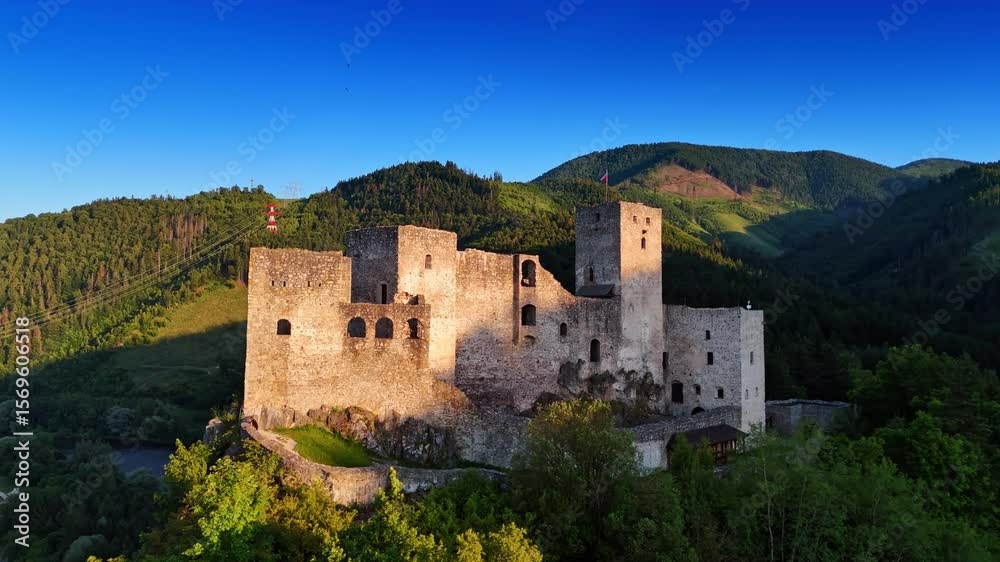 Historic castle ruins in a green valley. Ancient castle ruins rise amid lush hills under a blue sky, showcasing stunning historical architecture.