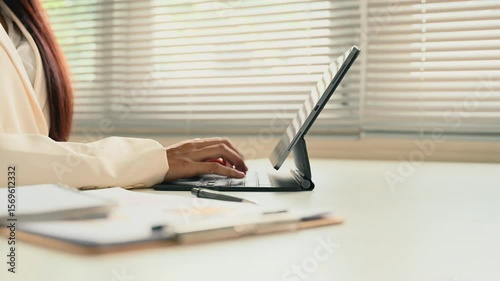 Close up of a businesswoman hands typing on a tablet keyboard at a modern office desk