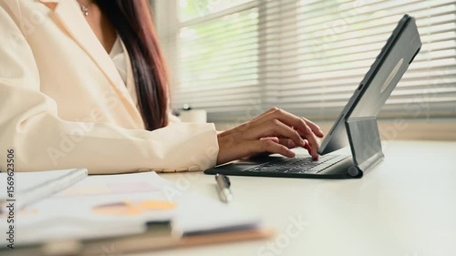Elegant businesswoman analyzing financial charts and graphs on digital tablet at her desk