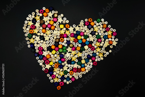 Wooden beads with colorful texture on a yellow background. A decorative accessory for handmade heart-shaped jewelry. 