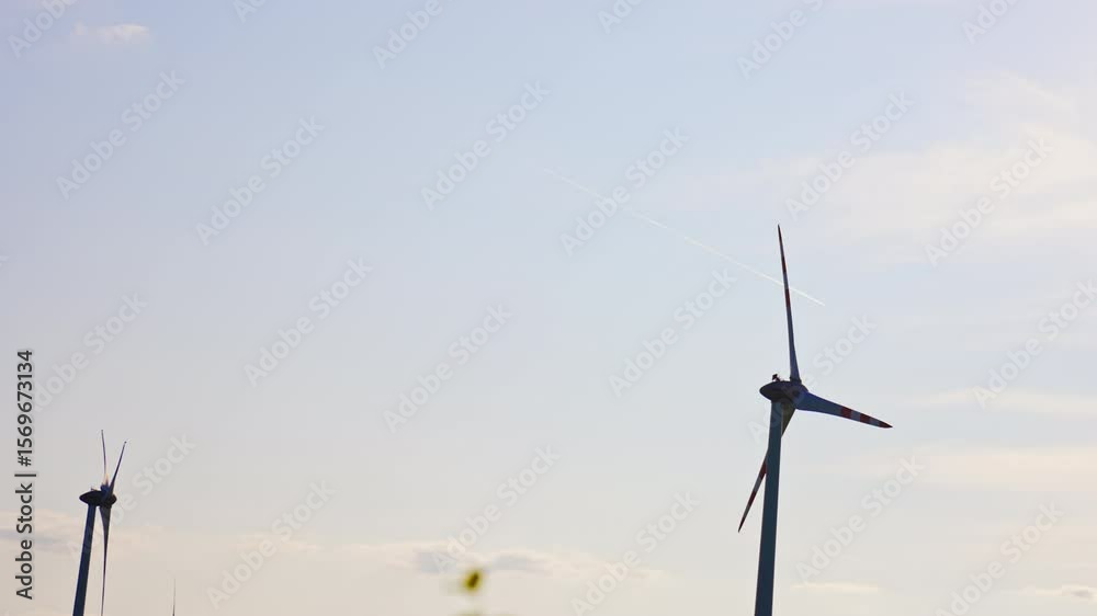 Wind turbines generating clean energy. Wind turbines spin against a blue sky, harnessing wind energy during the day in a serene landscape.