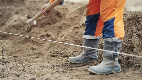 A diligent construction worker actively digging on a busy construction site while wearing essential safety gear