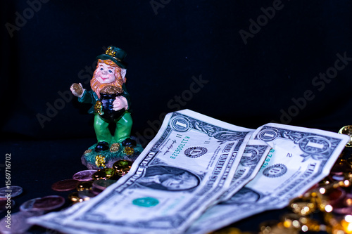 Leprechaun dressed in green behind a few dollars. The focal point is the dollars or money.