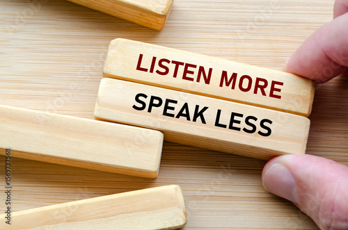 Listen more and speak less phrase on wooden blocks, a reminder to practice thoughtful listening before reacting, especially in leadership and teamwork