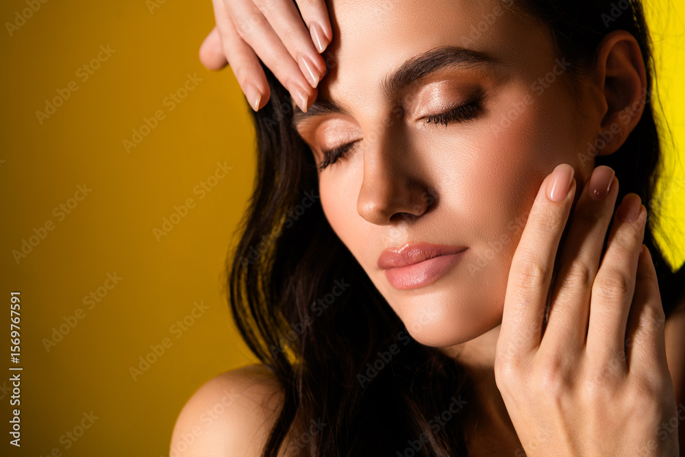 Naklejka premium Gorgeous brunette woman with glowing makeup and elegant charm posing against vibrant yellow background