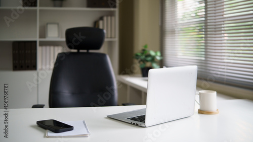 White minimalist desk with laptop and a cup of coffee, ideal for productive work in a modern office.