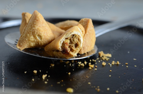 Fototapeta Naklejka Na Ścianę i Meble -  Mini dal samosa – small triangular deep-fried Indian snack filled with spicy lentil mixture, popular as tea-time or festive street food – crispy traditional savory