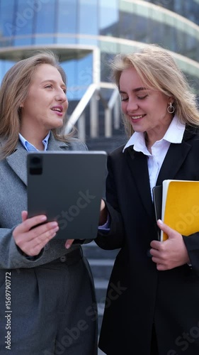 Businesswomen collaborating on a digital presentation in an urban setting 