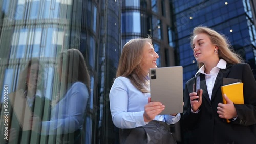 Friends engage with a tablet while exploring a city area on a sunny day.