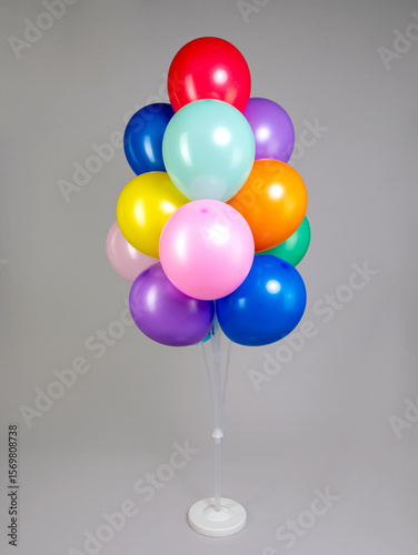 Multicolored balloons on white plastic stand isolated on gray background