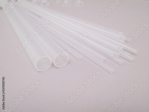 Transparent white tubes of different sizes on a gray background, space for text