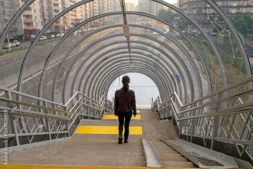 Voronezh, Russia, June 14, 2025: A girl descends the stairs in an overpass, seen from behind