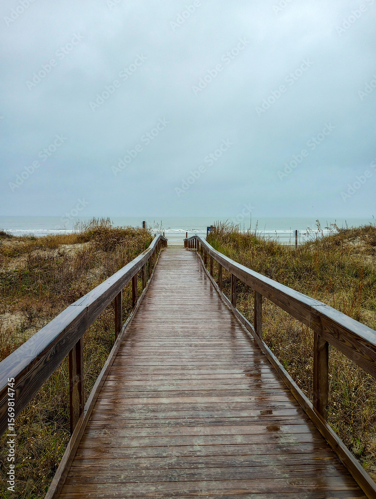 Obraz premium A pier going down to the ocean beach at Beachwalker Park on a rainy day, Kiawah Island, South Carolina