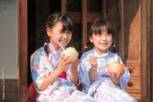 縁側でかき氷を食べる浴衣姿の姉妹