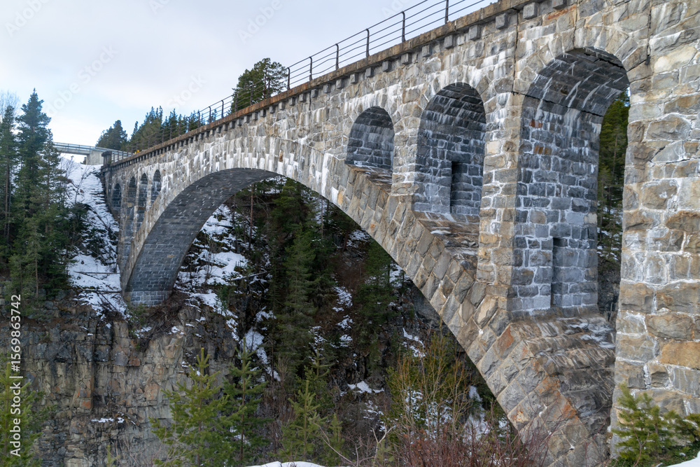 Fototapeta premium Historic stone viaduct bridge over snowy Norwegian gorge