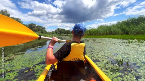 Kayaker paddling down green river on sunny day