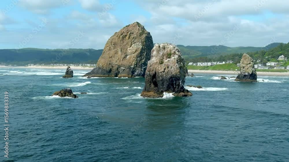 Orbiting aerial shot of waves crashing on Haystack Rock along the Oregon coast of the Pacific Ocean.