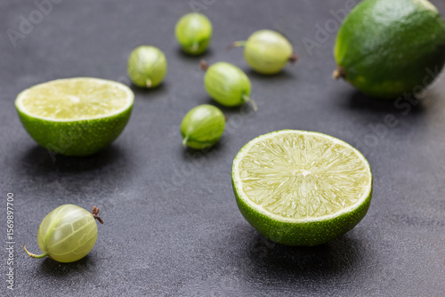 Lime halves and gooseberry berries on black background.