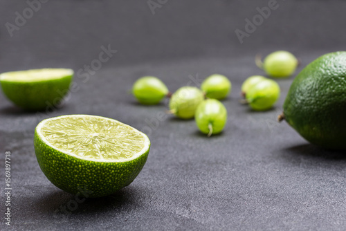 Lime halves and gooseberry berries on black background. Close up.