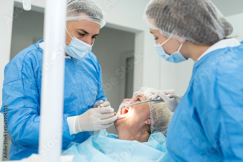 man dentists and female nurse examine the mouth of young elderly woman. Reception at dentist healthcare in the middle age