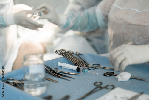 Nurse hands syringe with clear solution to surgeon. Sterile teamwork in vascular operating room.