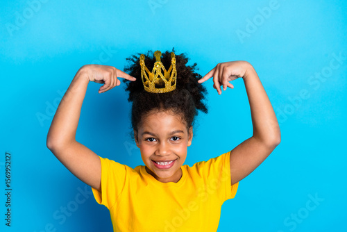 Foto Happy young girl pointing to a golden crown showing her confidence and self-este