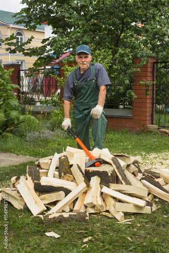 Elderly active man in prepares firewood for heating a bathhouse. He is pleased