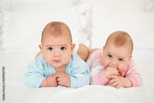 Canvastavla two babies, a boy and a girl on a white bed in a bedroom lying on their tummy, c