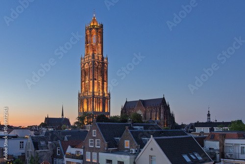 Experience the enchanting glow of a historic European city at dusk, highlighting the magnificent illuminated Dom Tower 