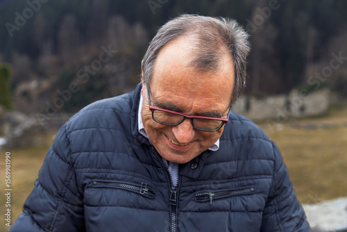 Mature caucasian male outdoors in winter jacket in scenic mountain landscape