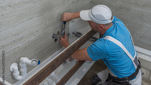 Installation of bathroom furniture. The plumber during a angle valve installation for a faucet.