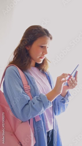 Young woman anxiously checking phone for updates about academic results. Ideal for digital learning platforms and contemporary student life stories