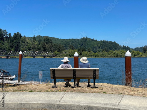 Couple sitting on a bench relaxing and enjoying a peaceful view of the Umpqua River